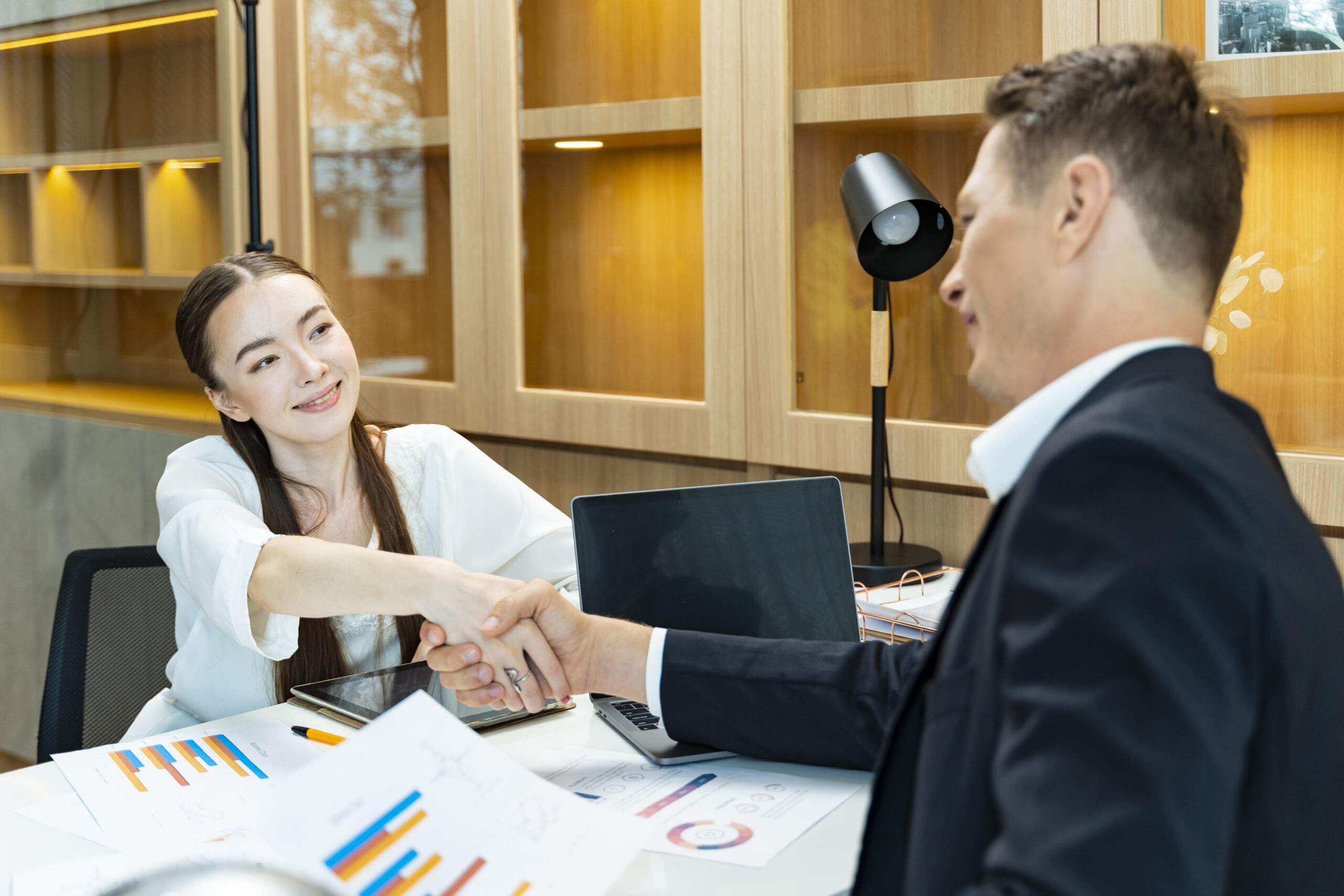 Caucasian business CEO congratulate female employee for the outstanding achievement of her team performance by shaking hand in the modern office workplace concept
